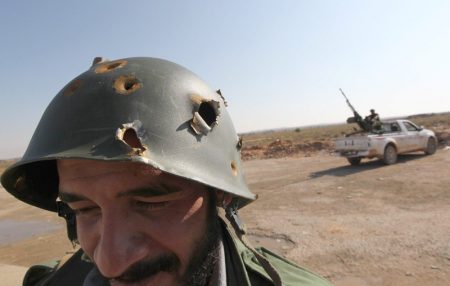 A Libya's National Transitional Council (NTC) fighter wear a bullet riddled helmet he found close to the frontline on the outskirts of the desert city of Bani Walid October 5, 2011 AFP PHOTO/KARIM SAHIB (Photo credit should read KARIM SAHIB/AFP/Getty Images)