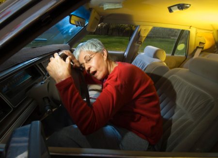 Woman asleep on steering wheel of car